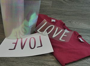 A picture showing a roll of DesignFilm™, some shirts, cut material, and a sheet for sublimation
