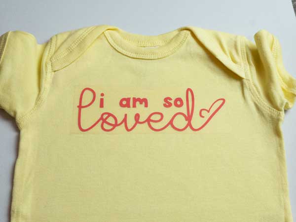 The onesie before pressing with the design laid out and ready to be pressed.