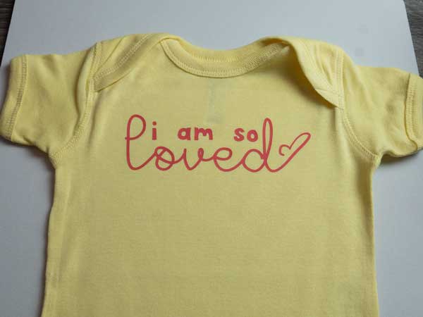 The finished onesie, showing the words "I am so loved" pressed onto a onesie in ThermoFlex Plus