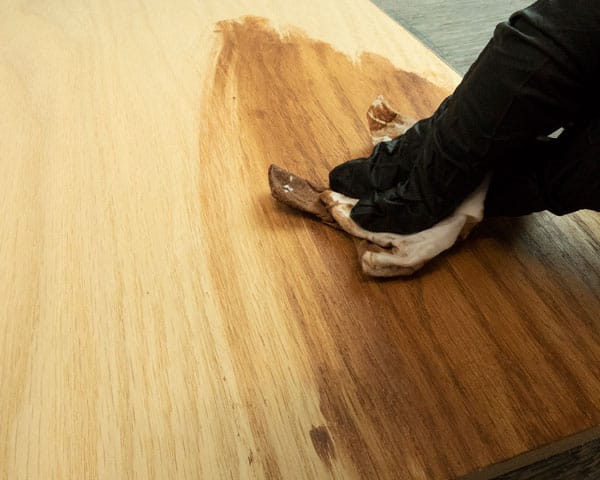 A piece of wood being stained with a baby wipe and acrylic paint.