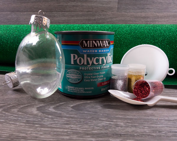 The supplies needed for this blog post- ornament, glitter, Pressure Sensitive GlitterFlex® Ultra, a funnel, and polycrylic