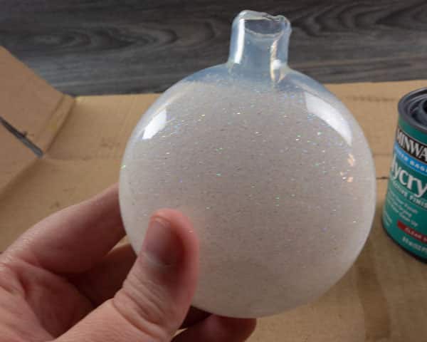 The ornament in process of spreading the glitter on the inside of the ornament via rolling