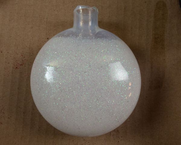 The glitter ornament in the middle of being rolled- there is a little bit of adhesive up top that still needs glitter rolled onto it