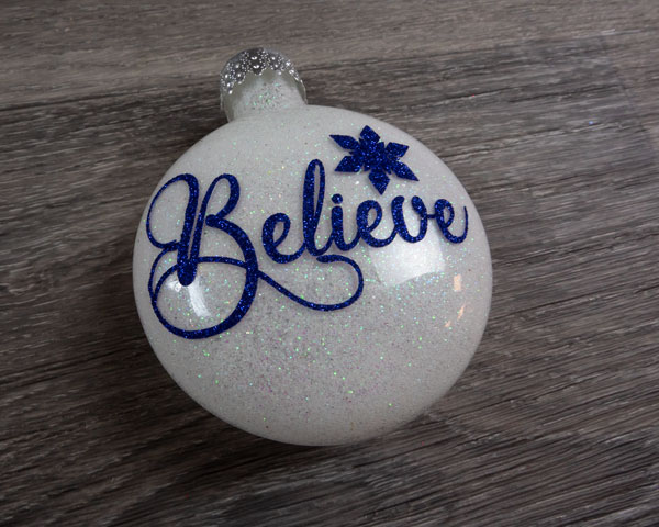 A finished ornament with the word "Believe" with white glitter on the inside using Pressure Sensitive GlitterFlex® Ultra