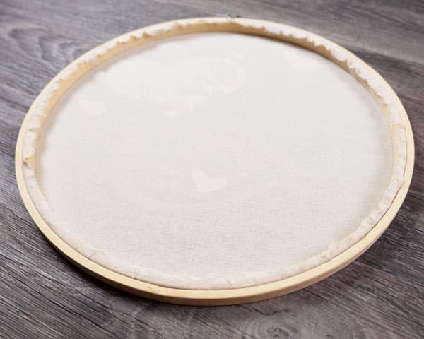 The embroidery hoop finished after the hot glue has been applied to keep the edges of the cloth down