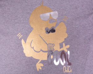 A shirt with a chick in sunglasses and a bowtie that reads "one cool chick" in Super Gold and Brilliant Silver DecoFilm